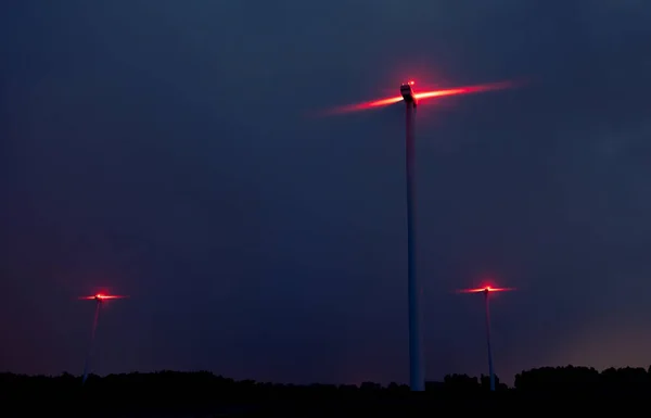 Вітрові турбіни на драматичних темно-синіх хмарах на небі. Буря наближається. Червоний попереджувальний світло на вітряк . — стокове фото