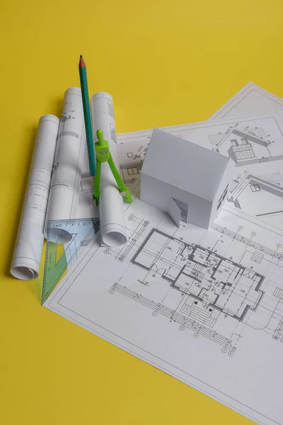 White family paper house, house projects plan and blueprints in the background. Minimalistic and simple concept, style. Horizontal orientation. View from above — Stock Photo, Image