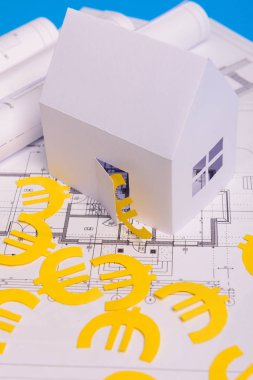 Kağıt gökdelenler, avro parası, ev projeleri planı ve mavi arkaplan kağıdındaki planlar. Minimalist ve basit bir kavram, tarz. Yatay oryantasyon. Yukarıdan görüntüle