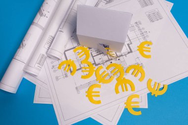 Kağıt gökdelenler, avro parası, ev projeleri planı ve mavi arkaplan kağıdındaki planlar. Minimalist ve basit bir kavram, tarz. Yatay oryantasyon. Yukarıdan görüntüle
