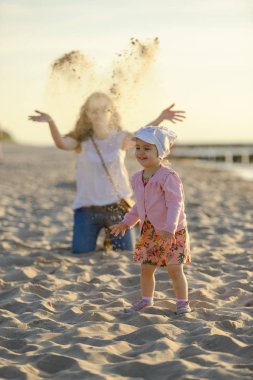 Anne ve küçük kızı sahilde oynuyorlar. Otantik resim