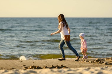 Anne ve küçük kızı sahilde oynuyorlar. Otantik resim