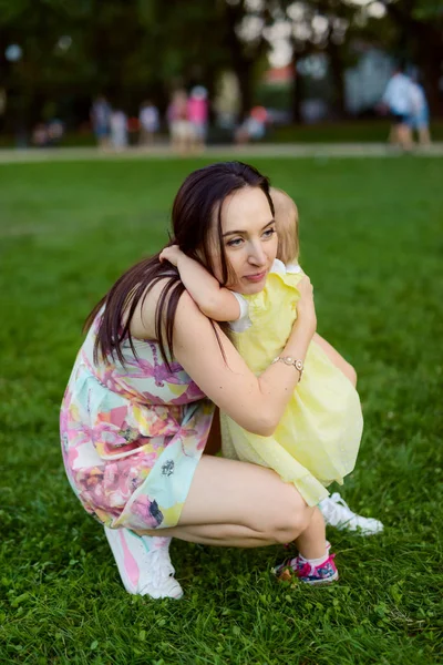 Happy mother and daughter in the park. Beauty nature scene with family outdoor lifestyle. Happy family resting together on the green grass, having fun outdoor. Happiness and harmony in family life — Stock Photo, Image