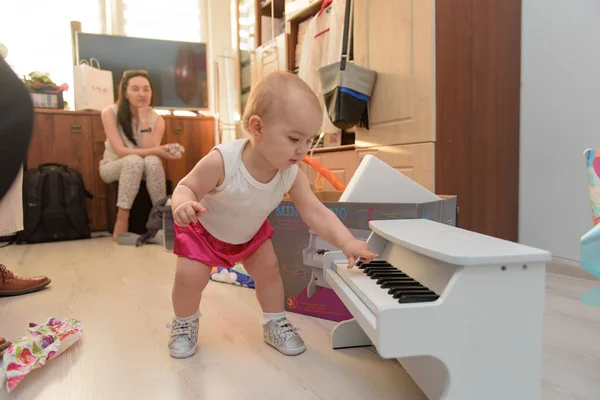 Hermosa niña jugando piano de juguete en la sala de luz. Auténtico i —  Fotos de Stock