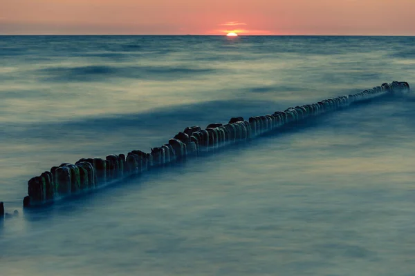 Fából készült víztörés naplementekor a Balti-tengeren — Stock Fotó