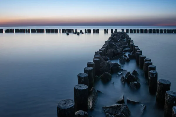 Houten golfbreker bij zonsondergang aan de Baltische Zee — Stockfoto
