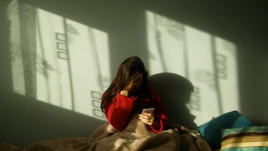 Üzgün kadın yatakta bir telefon görüşmesi yapıyor. Bunalımlı, şaşkın bir kadın yatakta oturuyor ve telefonu tutuyor..