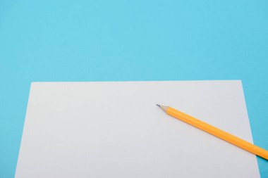 Boş kağıt ve mavi arka planda sarı kalemler. Yukarıdan görüntüle