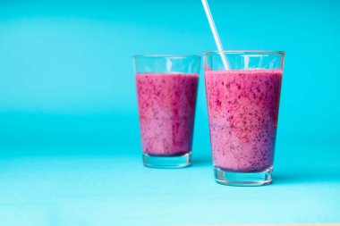 Mavi arka planda kahvaltıda taze böğürtlen, chia tohumu ve muz ile yabanmersini smoothie, seçici odak