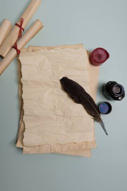 Kuzgun tüyü, mürekkep hokkası ve kırmızı arka planda eski sarı kağıt. Uzayı kopyala Eski mektup.