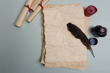 Kuzgun tüyü, mürekkep hokkası ve kırmızı arka planda eski sarı kağıt. Uzayı kopyala Eski mektup.