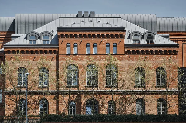 Trees in front of a red brick building — Stock Photo, Image