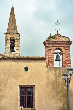 İtalya 'nın Toscana kentindeki Magliano köyünde çan kulesi ve çan kulesi olan taştan bir kilisenin duvarı.