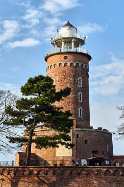 A red brick lighthouse at the entrance to the port in the city of Kolobrzeg clipart