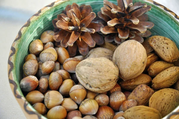 Nueces, avellanas y almendras en cáscaras, una sobre otra en tazón de cerámica — Foto de Stock