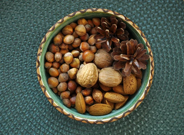 Грецкие орехи, фундук и миндаль в раковинах, один на другой в керамической миске — стоковое фото