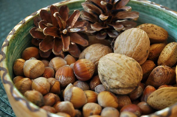 Walnoten, hazelnoten en amandelen in shells, één op de andere in keramische kom — Stockfoto