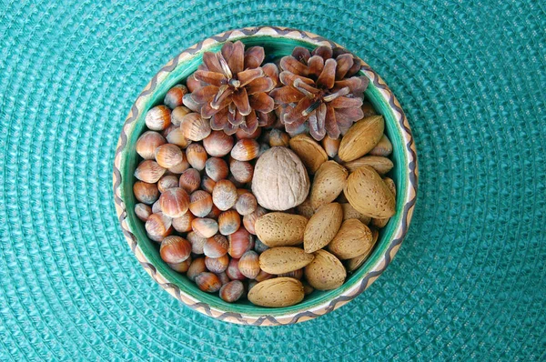 Nueces, avellanas y almendras en cáscaras, una sobre otra en tazón de cerámica — Foto de Stock