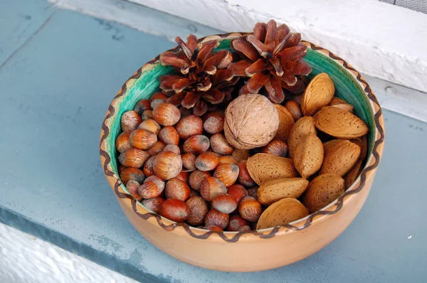 Nueces, avellanas y almendras en cáscaras, una sobre otra en tazón de cerámica — Foto de Stock