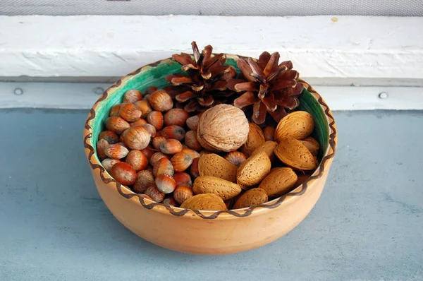 Nueces, avellanas y almendras en cáscaras, una sobre otra en tazón de cerámica — Foto de Stock