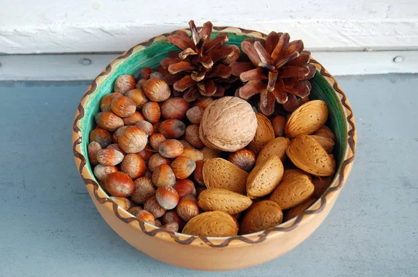 Грецкие орехи, фундук и миндаль в раковинах, один на другой в керамической миске — стоковое фото