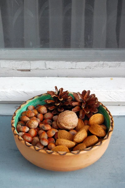 Nueces, avellanas y almendras en cáscaras, una sobre otra en tazón de cerámica — Foto de Stock