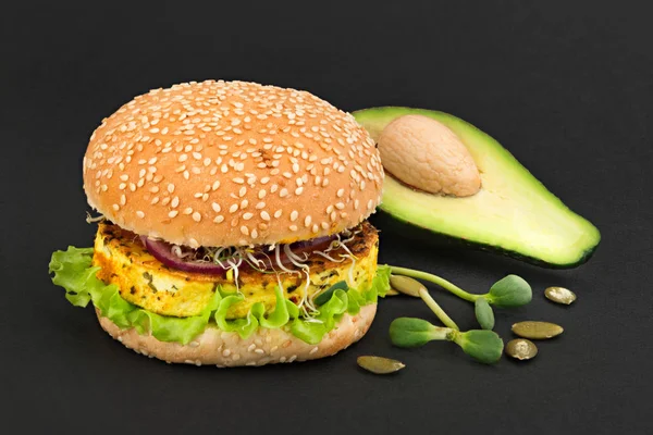 Vegetarian burger and ingredients on black background