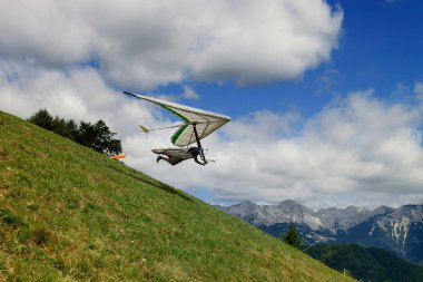 Pilot bir yeşil çimenli yamaç th içinde yüksek bir hang glider ile çalışır
