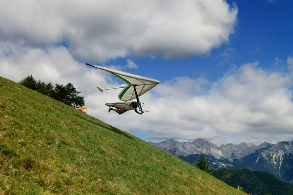 녹색 잔디 슬로프 일에서 높은에 행글라이더와 파일럿 실행 — 스톡 사진