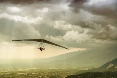 Cesur aşırı hangglider pilot kanatları büyük yağmur fırtına bulutları ile fırtınalı bir havada uçan dramatik atış.