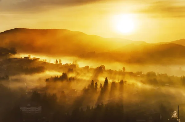 Nascer do sol enevoado brilhante em uma aldeia de montanha — Fotografia de Stock