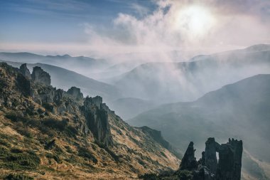 Vadiden yükselen bulutlarla dramatik dağ manzarası. 