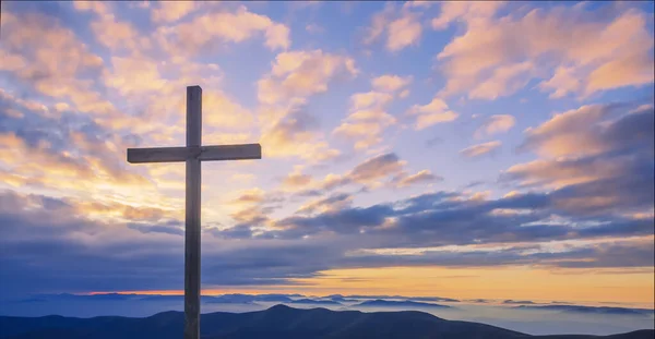 Korsa på en bergstopp med vacker solnedgång himmel — Stockfoto