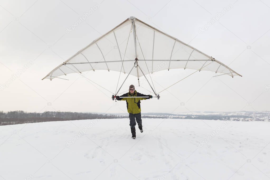 Happy man holds vintage hang glider wing.