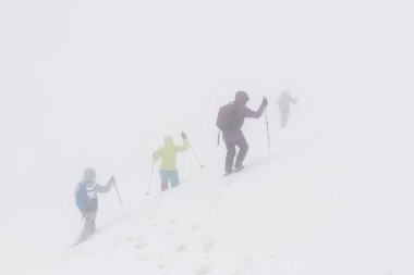 Dağlarda derin kar ve kötü hava koşulları olan bir grup yürüyüşçü.