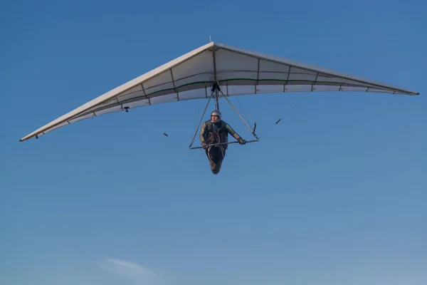 Hang glider pilot and his wing. Hangglider wing against bright blue sky.