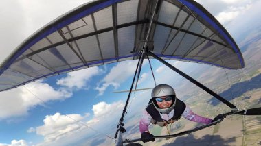 Mutlu gülümseyen kadın planör pilotu gökyüzünde kümülüs bulutlarıyla birlikte. Eylem kamerasıyla selfie