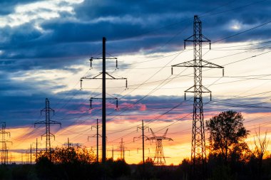 Canlı günbatımı gökyüzüne karşı elektrik hatları. Sanayi manzarası