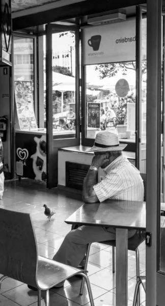 Sénior senta-se em um café calçadão na madeira — Fotografia de Stock