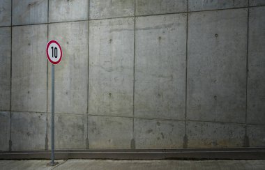 Trafik işareti önünde çıplak beton duvar  
