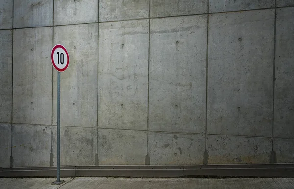 Segnale stradale di fronte al muro di cemento nudo — Foto Stock