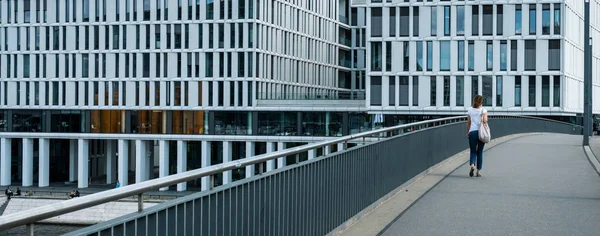 A woman walks alone over a bridge at berlin main station — 스톡 사진