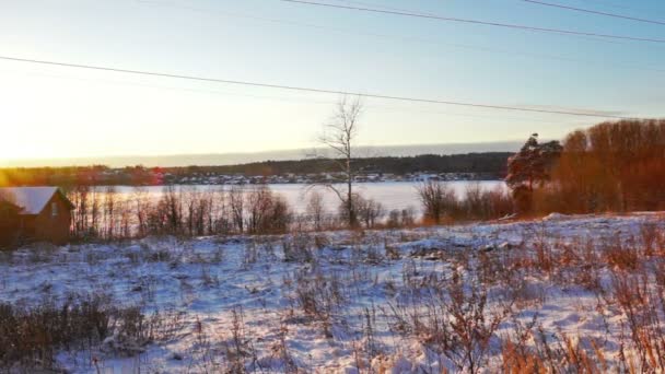 Casa de madeira em uma costa do lago nevado no pôr do sol de inverno — Vídeo de Stock