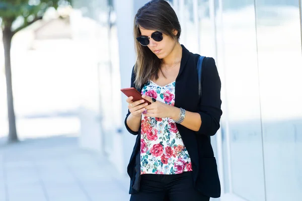 Vacker ung kvinna med hennes mobiltelefon på gatan. — Stockfoto