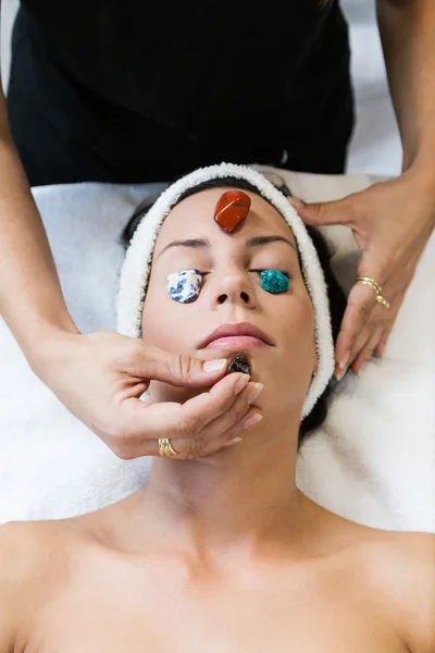 Hermosa joven que recibe terapia de piedras preciosas en el spa . — Foto de Stock