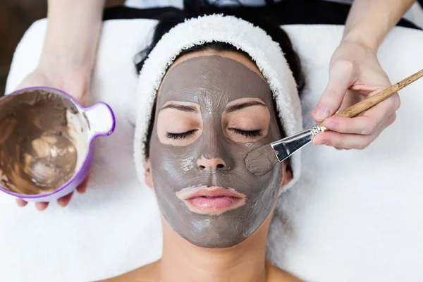 Schöne junge Frau mit Tongesichtsmaske im Beauty-Spa. Entgiftung — Stockfoto