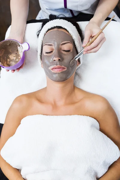 Beautiful young woman with clay facial mask in beauty spa. Detox — Stock Photo, Image