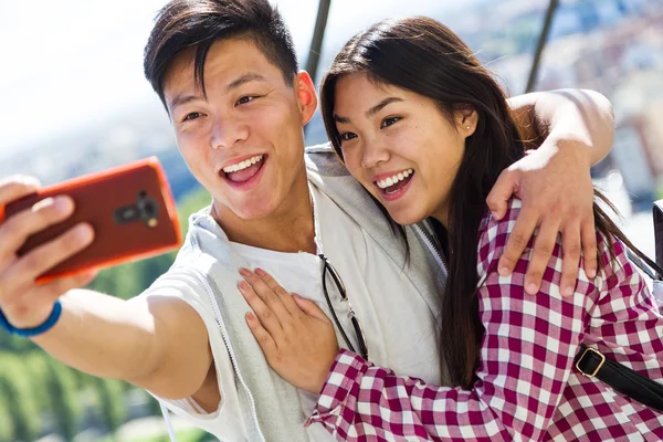 Feliz pareja joven usando el teléfono móvil en la ciudad . — Foto de Stock