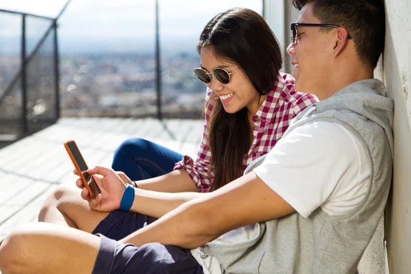 Glada unga par med hjälp av mobiltelefon i staden. — Stockfoto