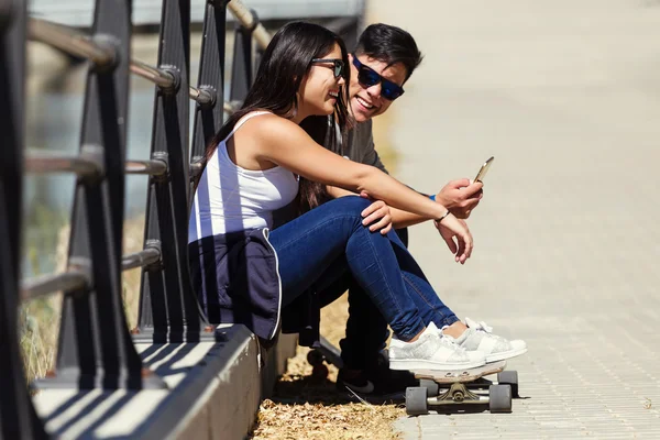 Két korcsolyázók használ mozgatható telefon-az utcán. — Stock Fotó